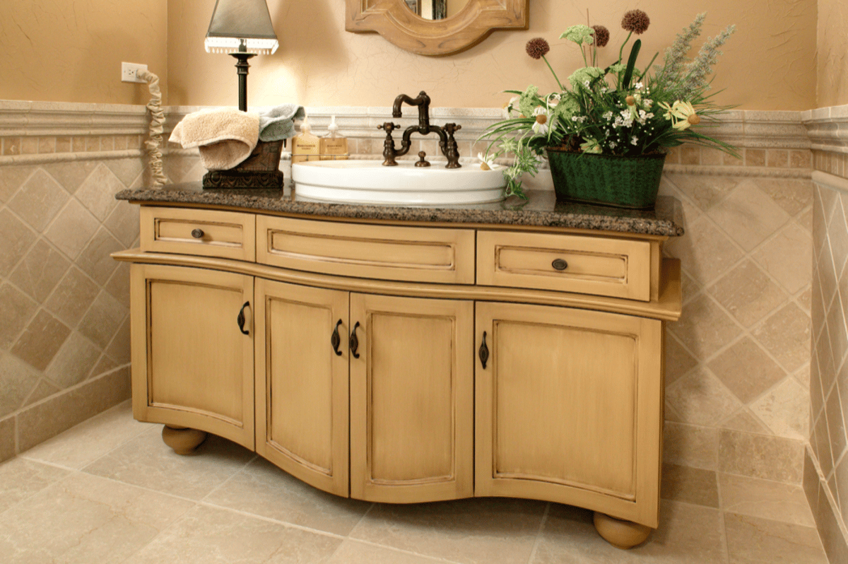 Cream vanity with vessel sink and stone tile walls