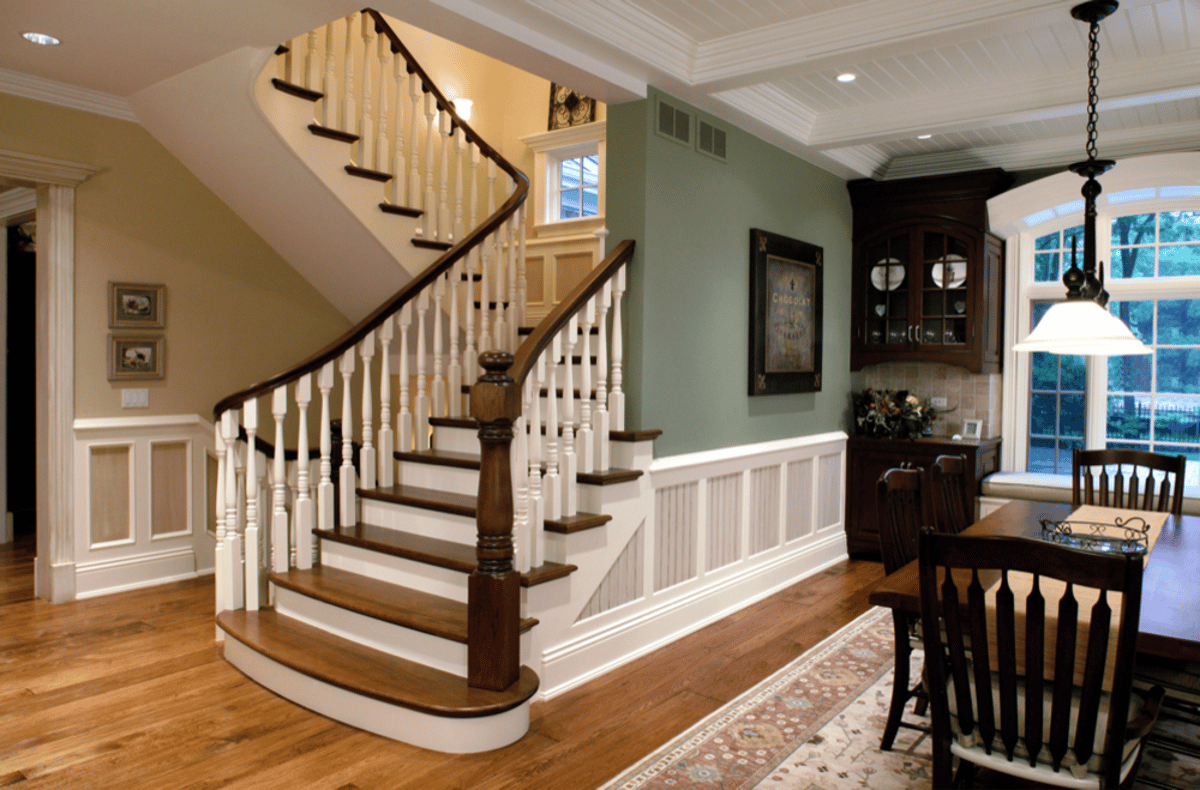 Curved staircase with white balusters and paneled wall