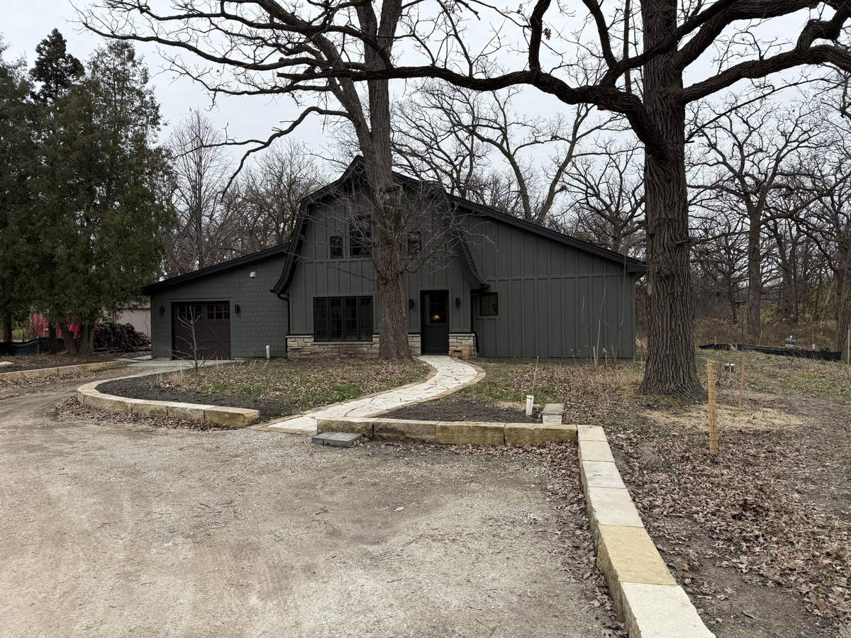 Expanded building with dark siding and landscaped entry