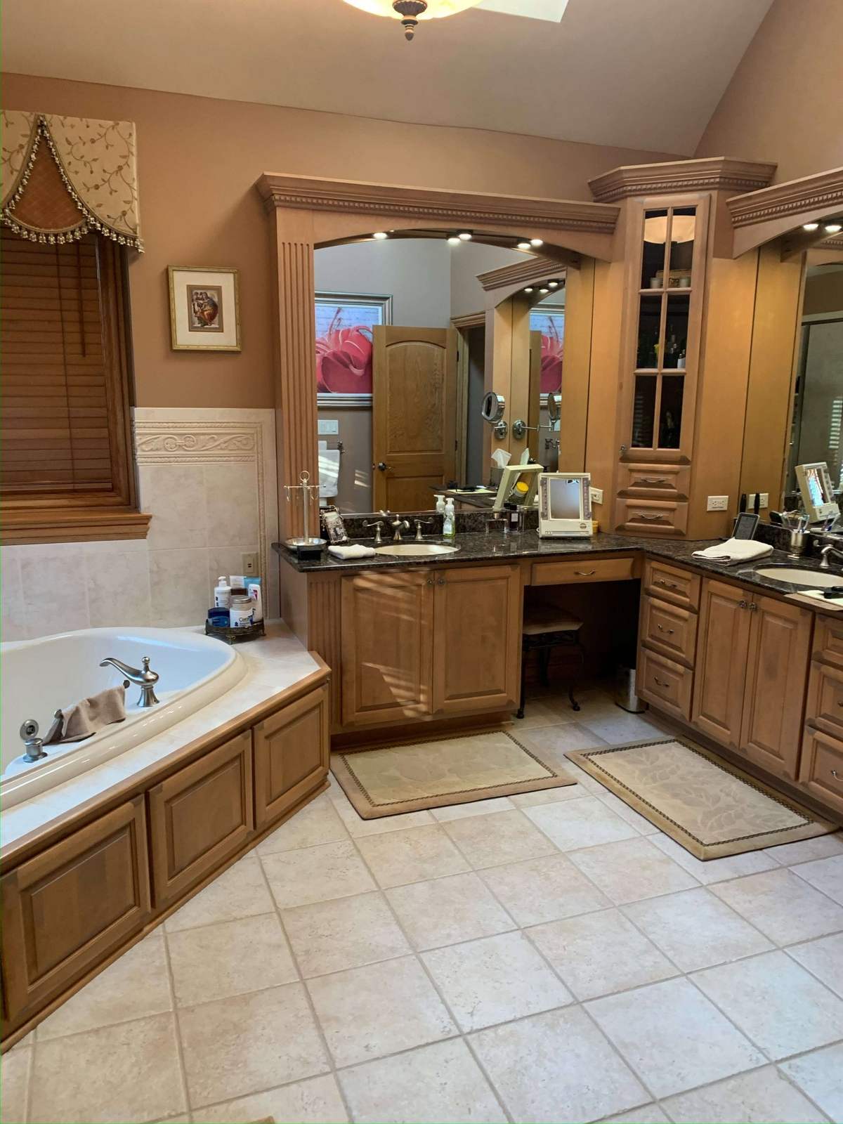 Bathroom before remodeling with wood vanity and corner tub