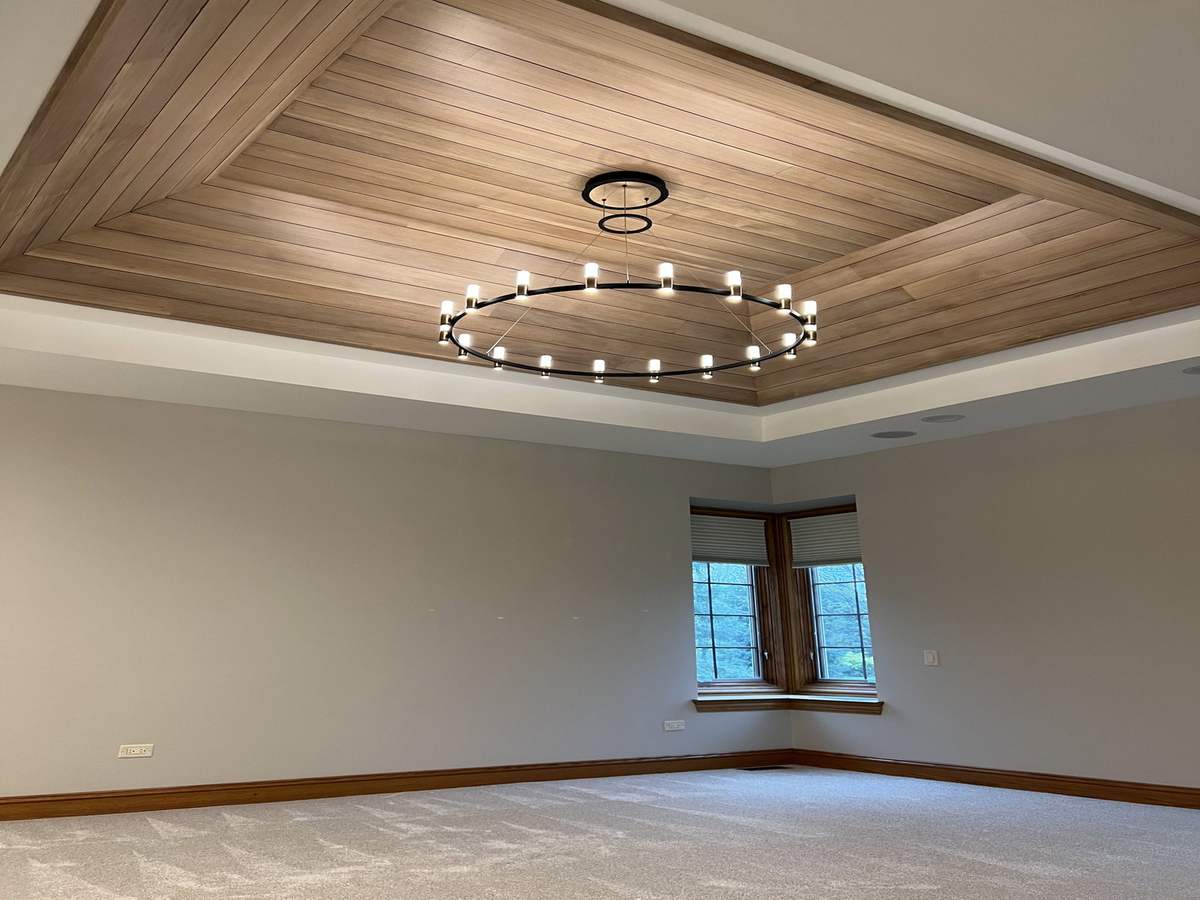 Wood-paneled tray ceiling with circular chandelier