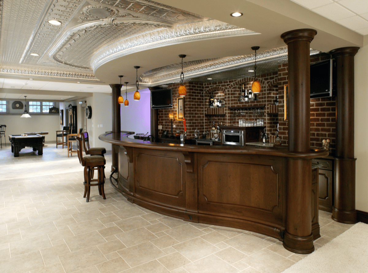 Curved wood basement bar with brick backsplash