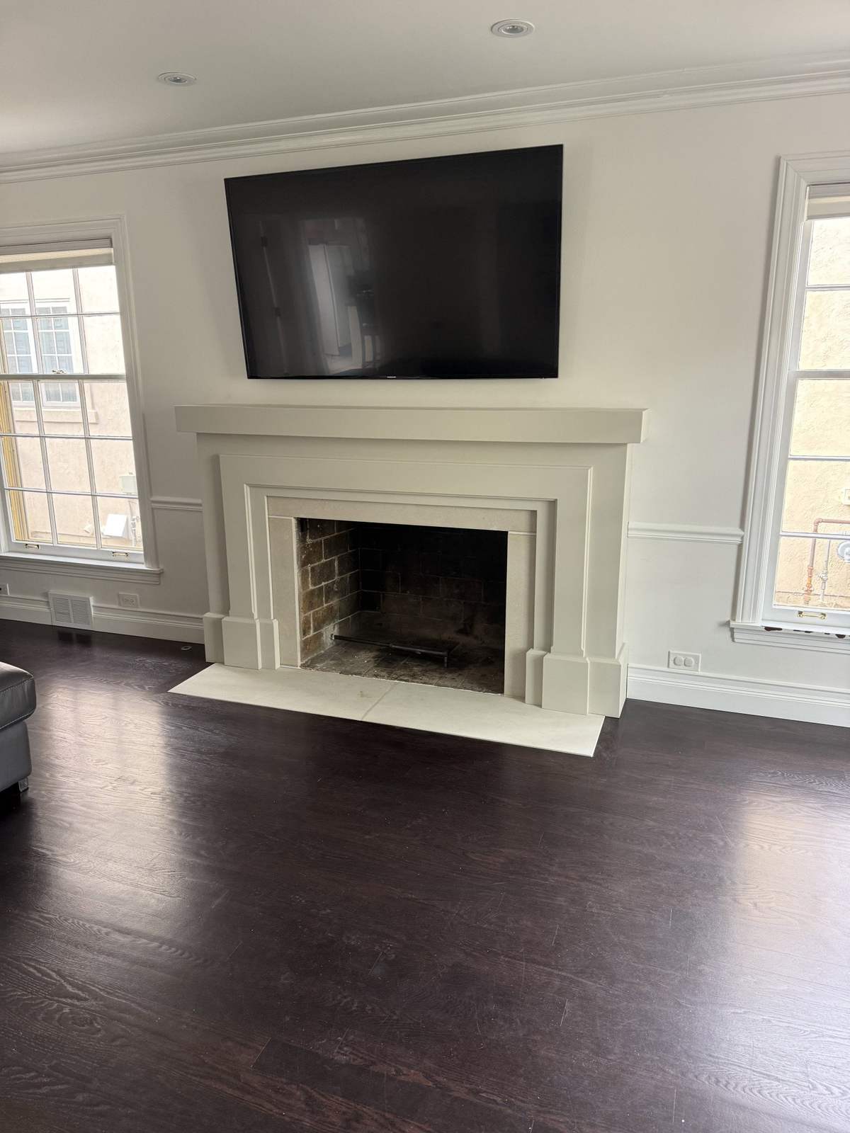 Remodeled fireplace wall with white surround and raised TV