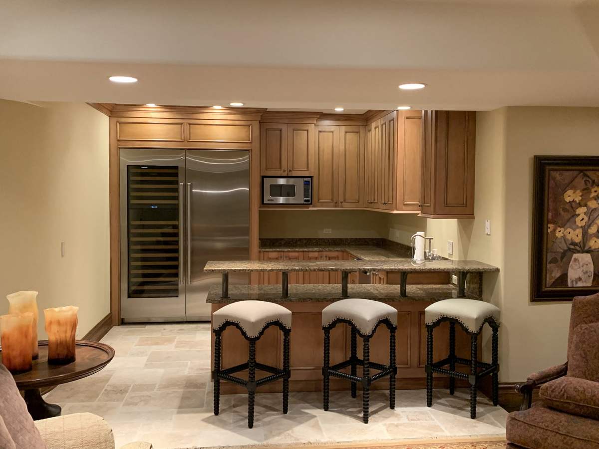 Kitchenette with wood cabinets and upholstered bar stools