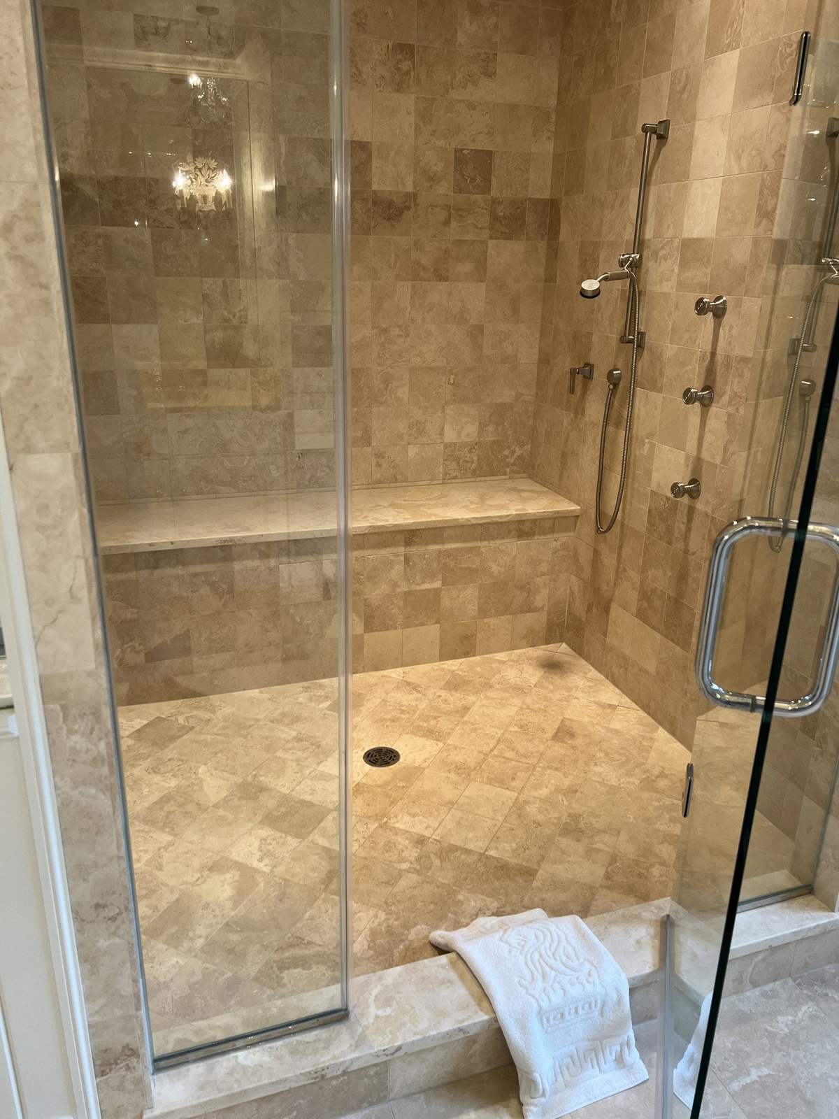 Shower before remodeling with beige stone tile