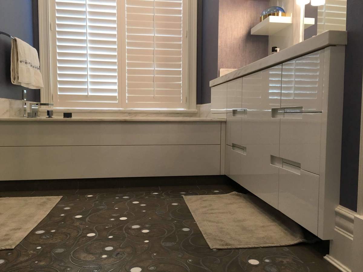 Gray bathroom cabinets beside a shuttered window
