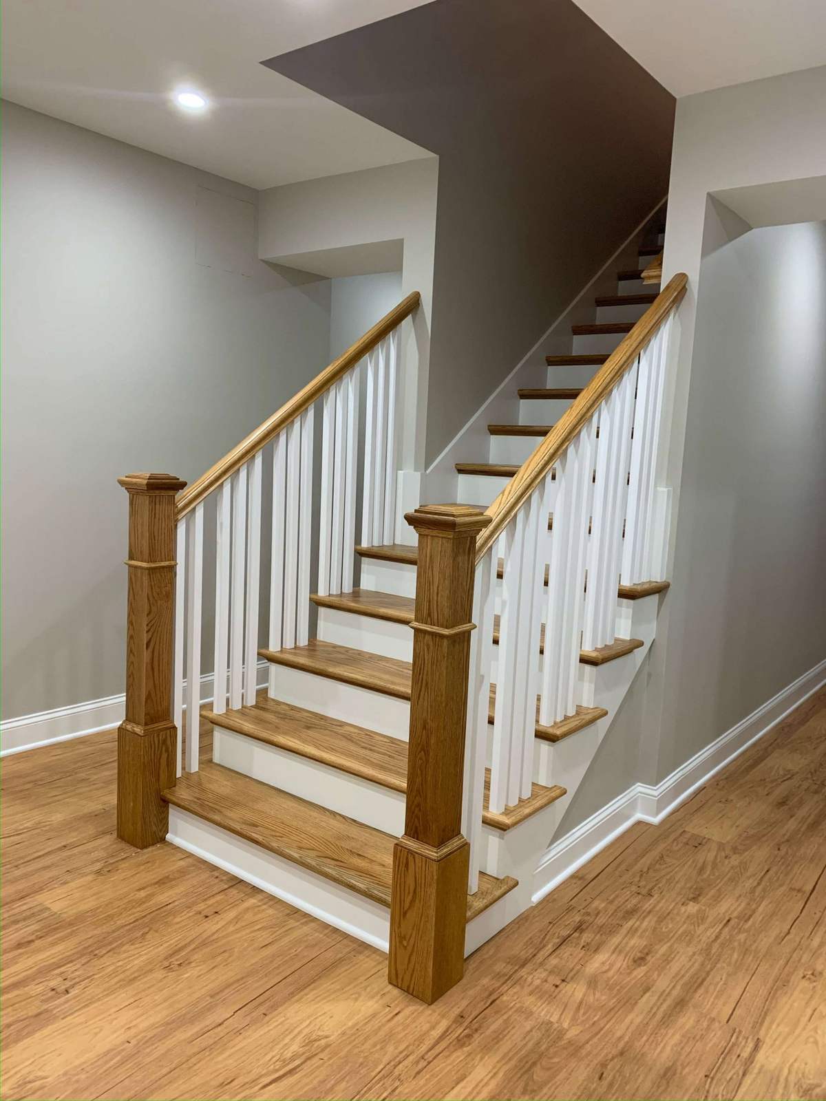 Finished basement staircase with white balusters and wood treads
