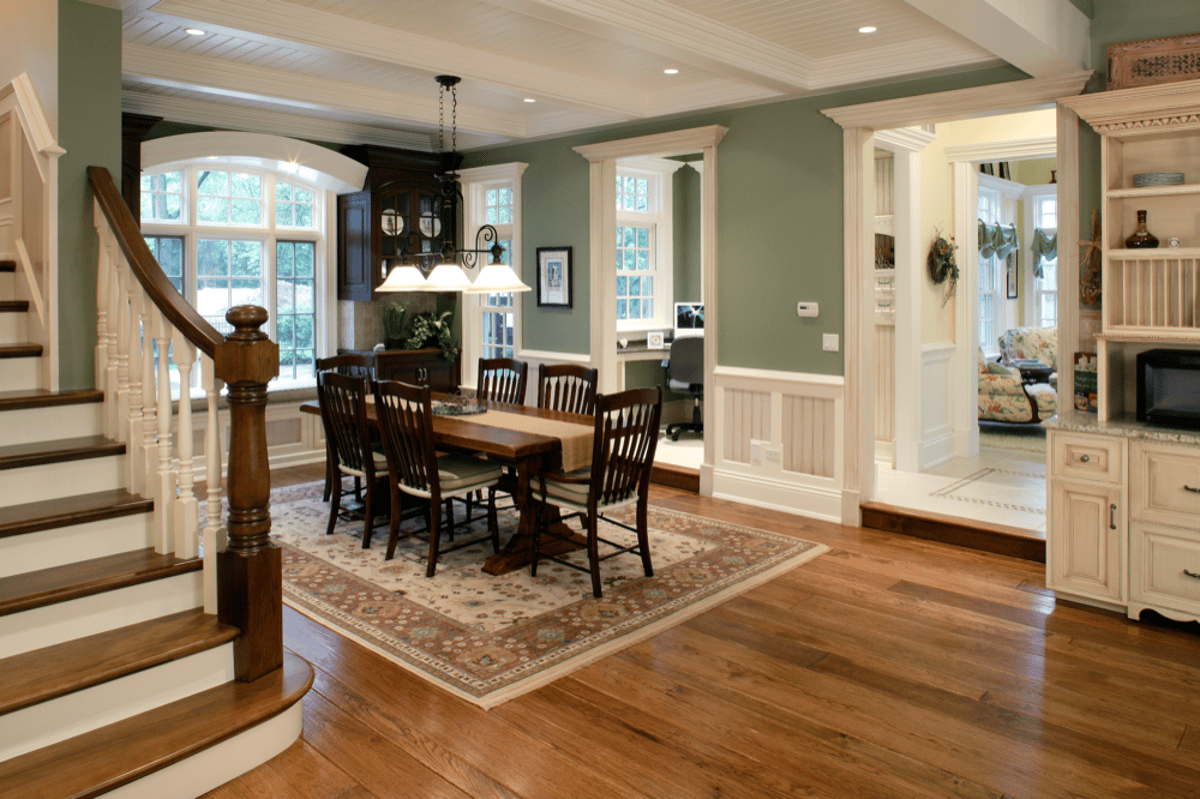 Dining space beside a wood staircase and kitchen