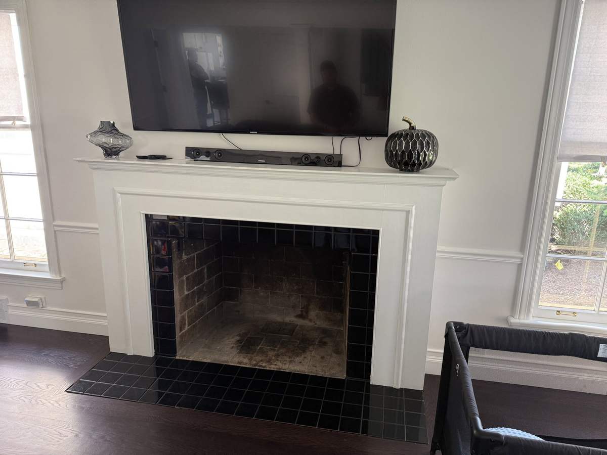 Fireplace wall before remodeling with dark firebox surround