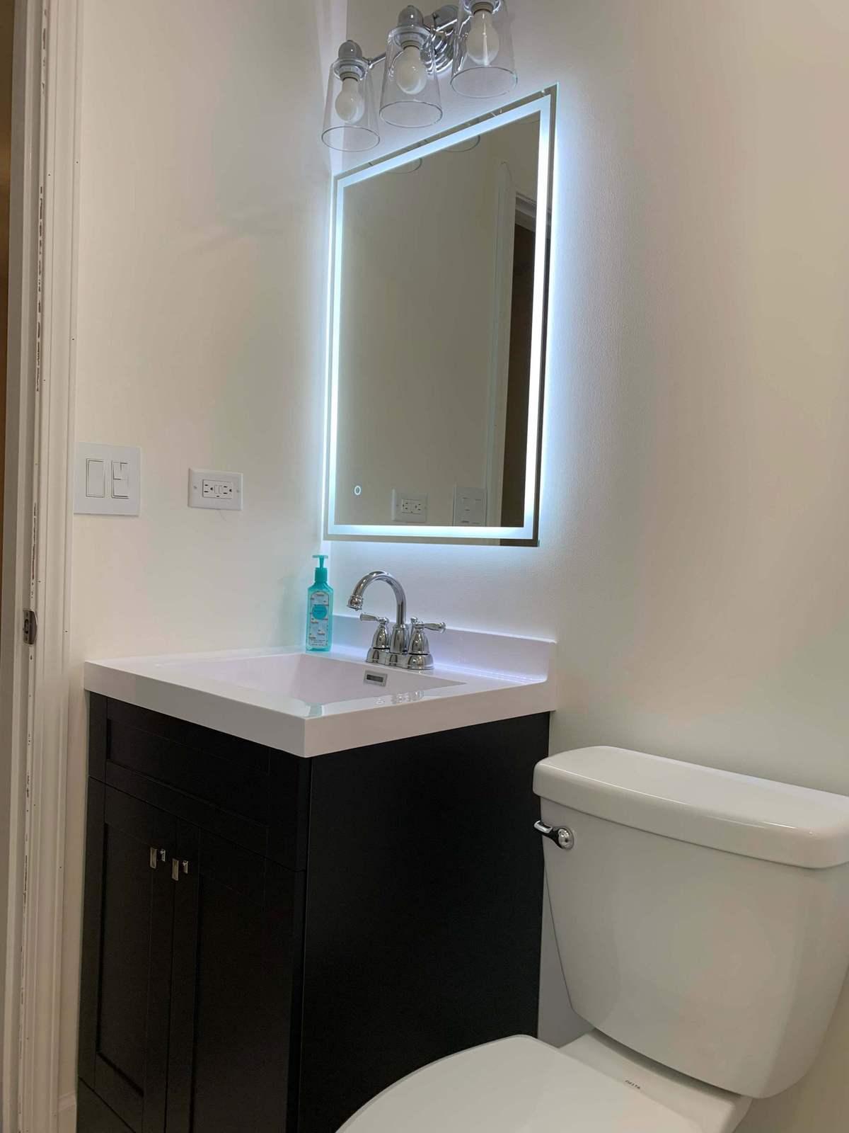Floating dark vanity with illuminated mirror