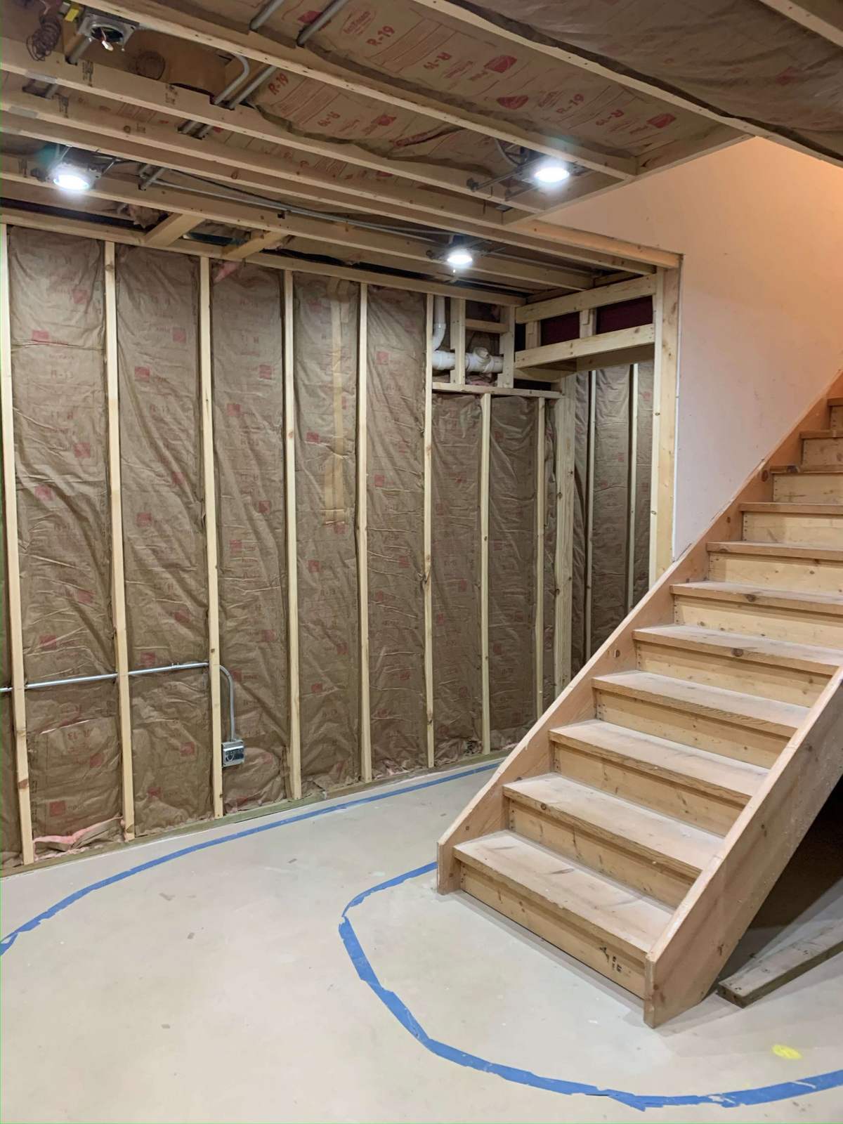 Unfinished basement staircase with exposed framing