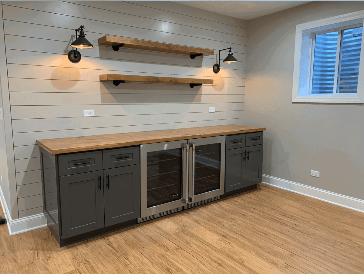 Basement beverage station with wood shelves and glass-front fridge
