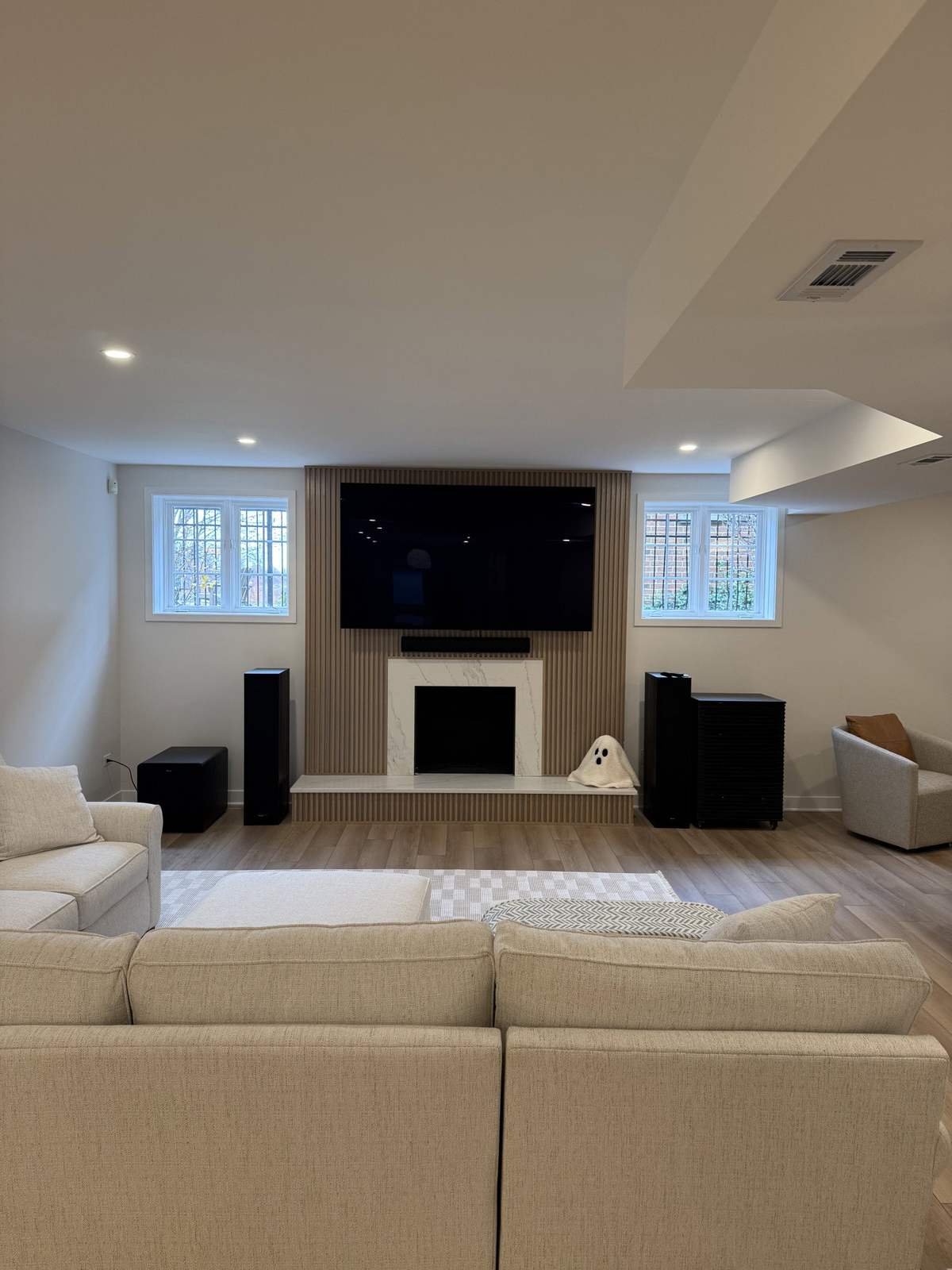 Finished basement TV lounge with white fireplace surround