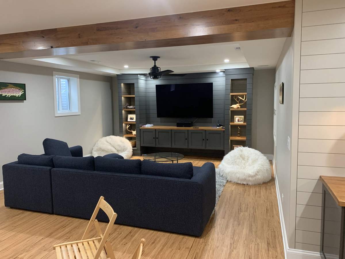 Basement TV lounge with ceiling beams and dark sofa