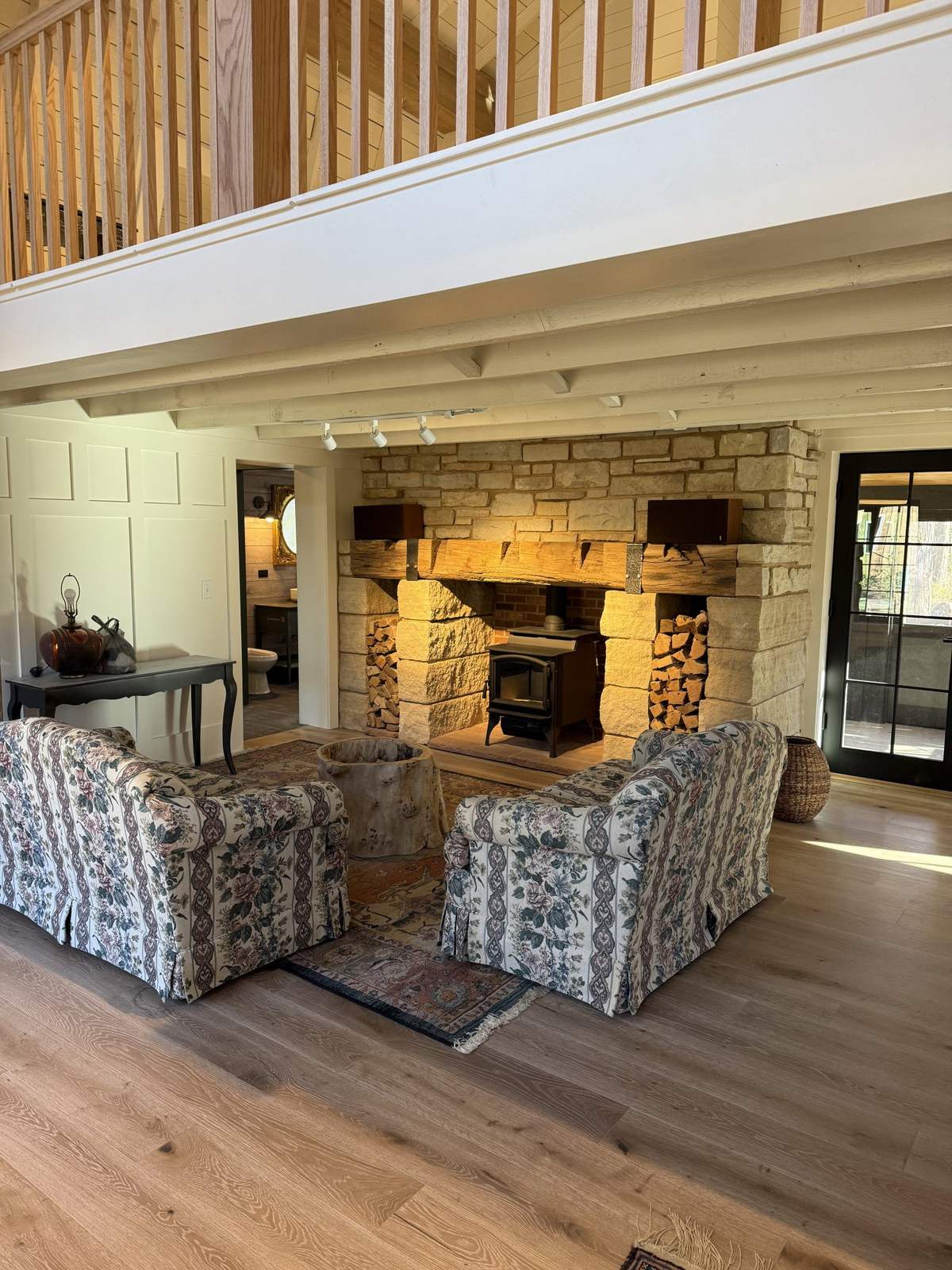 Finished living room with stone fireplace and loft railing